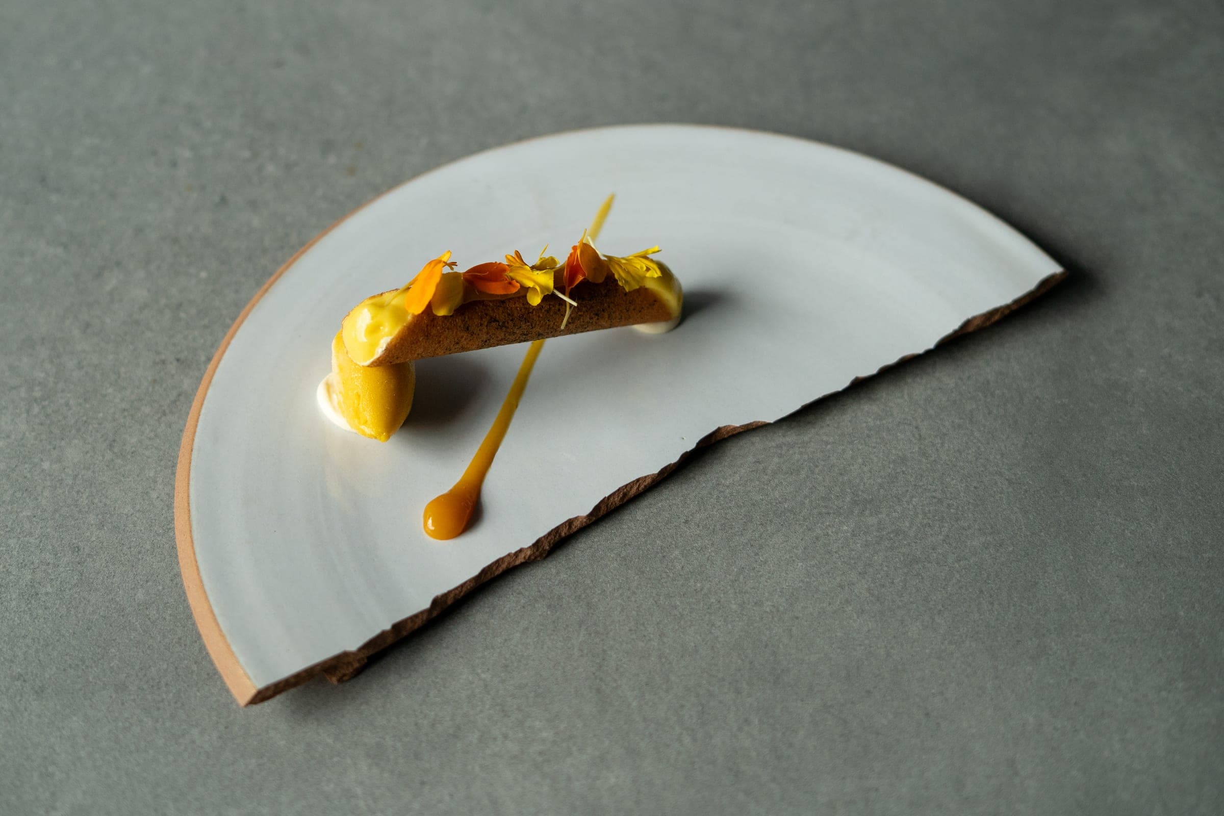 Dessert servi sur assiette en éventail, tuile croustillante, sorbet et fleurs comestibles