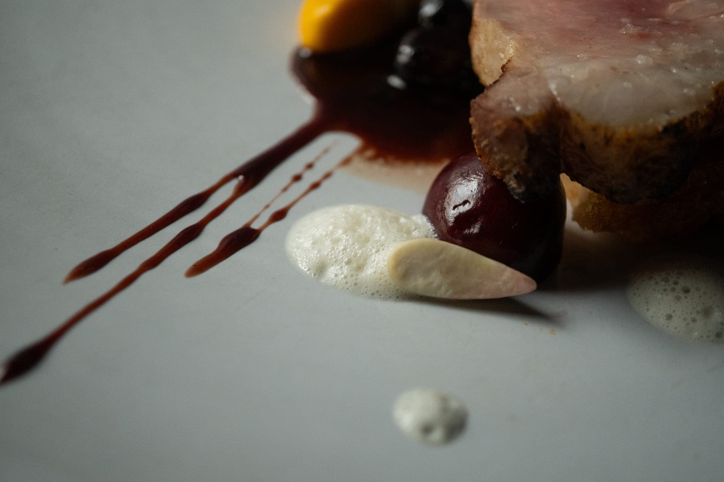 Plat de viande dressé avec sauce chocolatée et éléments croustillants