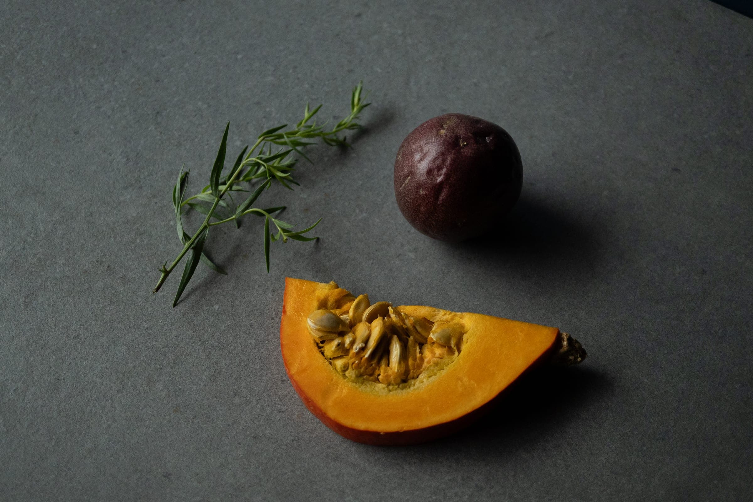 Nature morte : tranche de potimarron, fruit de la passion et brin d'herbe fraîche